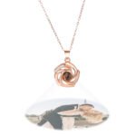 Rose gold heart-shaped pendant necklace with a black projection stone displaying a custom photo of a couple kissing, floating below the pendant.