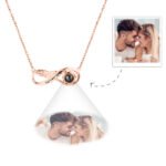 GPNL1177jpg - Printshop4me.au A rose gold infinity-shaped pendant necklace featuring a central black projection element and the engraving "Forever Love," displaying a customizable engraved photo below the pendant of a couple touching foreheads and smiling while holding coffee cups.