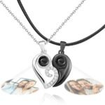 A pair of heart-shaped projection necklaces forming a yin-yang design, one in silver and one in black, each projecting a custom photo of a smiling couple, symbolizing love and connection.