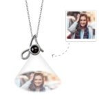 PNL1191A-0jpeg - Printshop4me.au A silver pendant necklace featuring a looped infinity-inspired design with a central black projection element, displaying a customizable engraved photo below the pendant of a smiling woman.