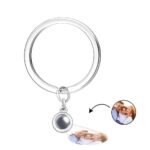 SKL1901A-fbe63060-a2c4-45bb-8c35-352610071f39-1jpg - Printshop4me.au A silver keychain with a circular projection element attached, displaying a customizable engraved photo below the projection of a smiling family of three.