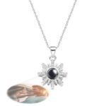 Personalized projection necklace in silver with sunburst pendant design, showing a custom photo of a couple in love projected beneath the black center, with the couple's photo inset in the top right corner.