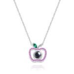 Silver necklace with an apple-shaped pendant adorned with pink gemstones and a green leaf, featuring a black photo projection sphere in the center