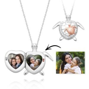 Customizable turtle locket necklace showing a silver and rose gold turtle design. The locket opens to reveal two heart-shaped photo compartments with pictures of a mother and daughter. A small arrow points to one of the photos, indicating personalization. The turtle pendant is attached to a silver chain