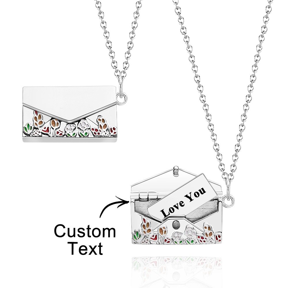 TKNL0P571X01jpg - Printshop4me.au A silver envelope-shaped pendant necklace with colorful floral cutout designs, showing a hidden compartment inside that can hold a customizable message card with text such as "Love You," hanging from a delicate silver chain.
