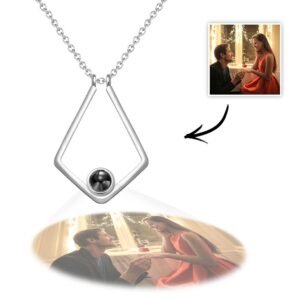 A silver geometric pendant necklace featuring a projection element at the base, displaying a customizable engraved photo below the pendant of a couple sharing a romantic moment by a window