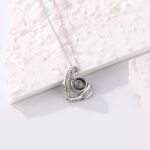 Silver pendant necklace with a blue pearl centerpiece and curved crystal-encrusted accents on a white textured background.