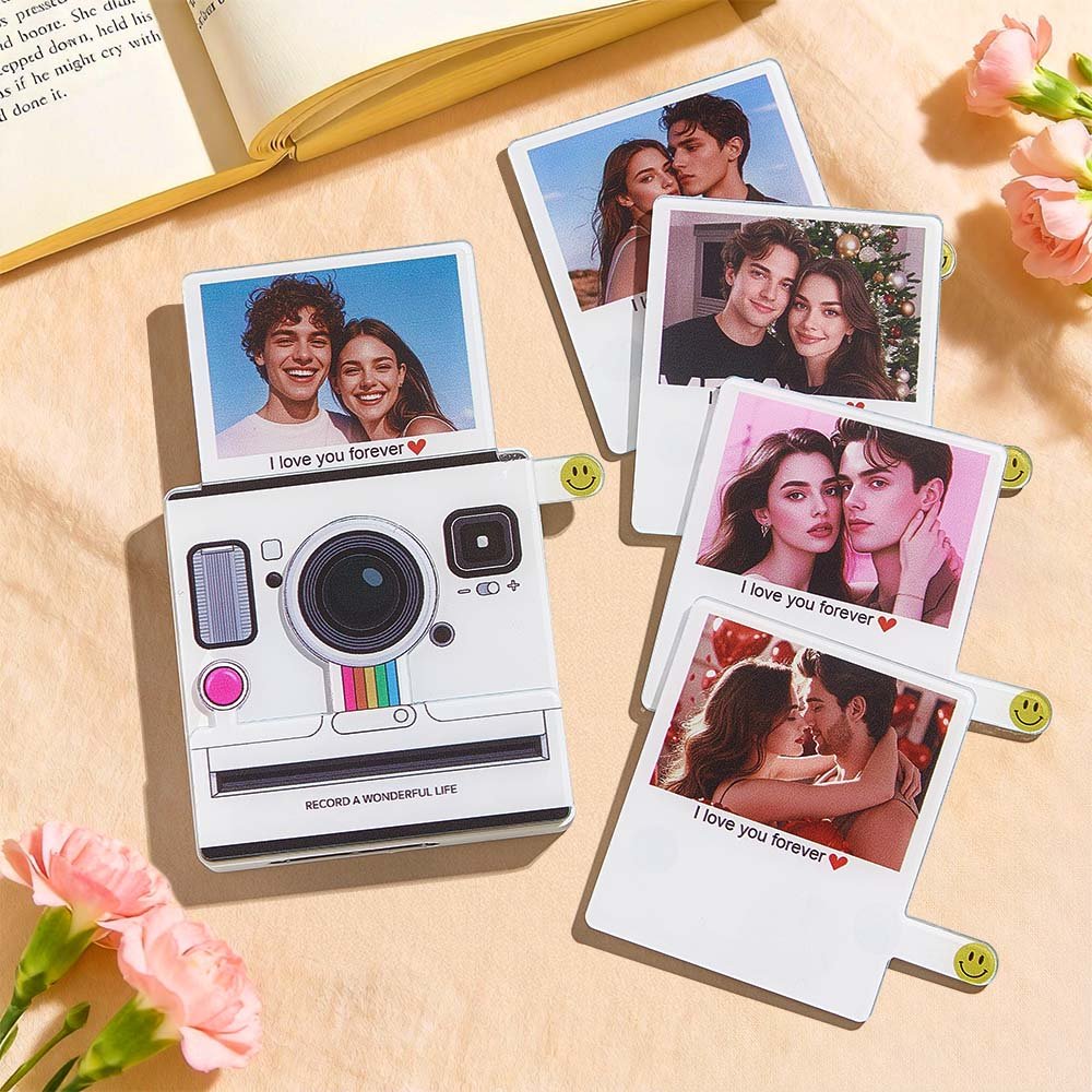 BXT0P1578X05jpg - Printshop4me.au Flat-lay of personalized Polaroid-style photo cards featuring couples’ portraits, including a camera-shaped photo card design with the text “I love you forever ❤️,” arranged on a wooden surface with flowers, a book, and warm aesthetic lighting.