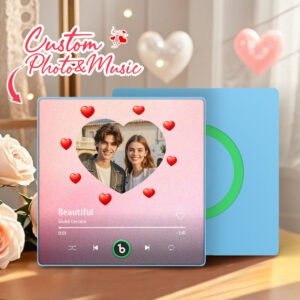 Personalized custom photo and music plaque featuring a couple’s photo inside a heart-shaped frame on a soft pink gradient background, surrounded by floating red heart icons. The design displays the song “Beautiful” by Giulio Cercato in a Spotify-style music player interface with playback controls and progress bar. The top includes the text “Custom Photo & Music.” A second blue panel with a green circular record-style design is placed behind the plaque in a romantic indoor setting.