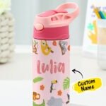 Personalized pink kids' stainless steel water bottle with flip-top straw lid and carry handle, featuring jungle animals including a sloth, koala, toucan, crocodile, tiger, and rhino. The bottle is customized with the name "Lulia" and displayed on a desk with a "Custom Name" label.
