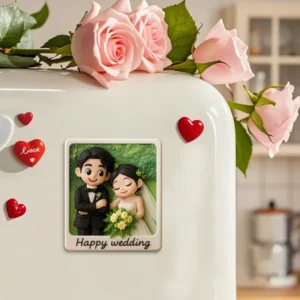 Close-up of a white refrigerator decorated with red heart magnets and pink roses on top. A personalized wedding-themed magnet is displayed featuring a cartoon bride and groom holding a bouquet, with the text “Happy wedding” below. The design has a soft, romantic style with a warm indoor background.